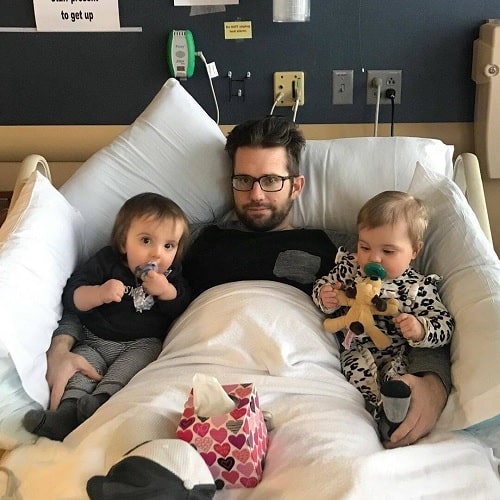 A picture of Nick Pendergrast in his bed in hospital along with his kids.